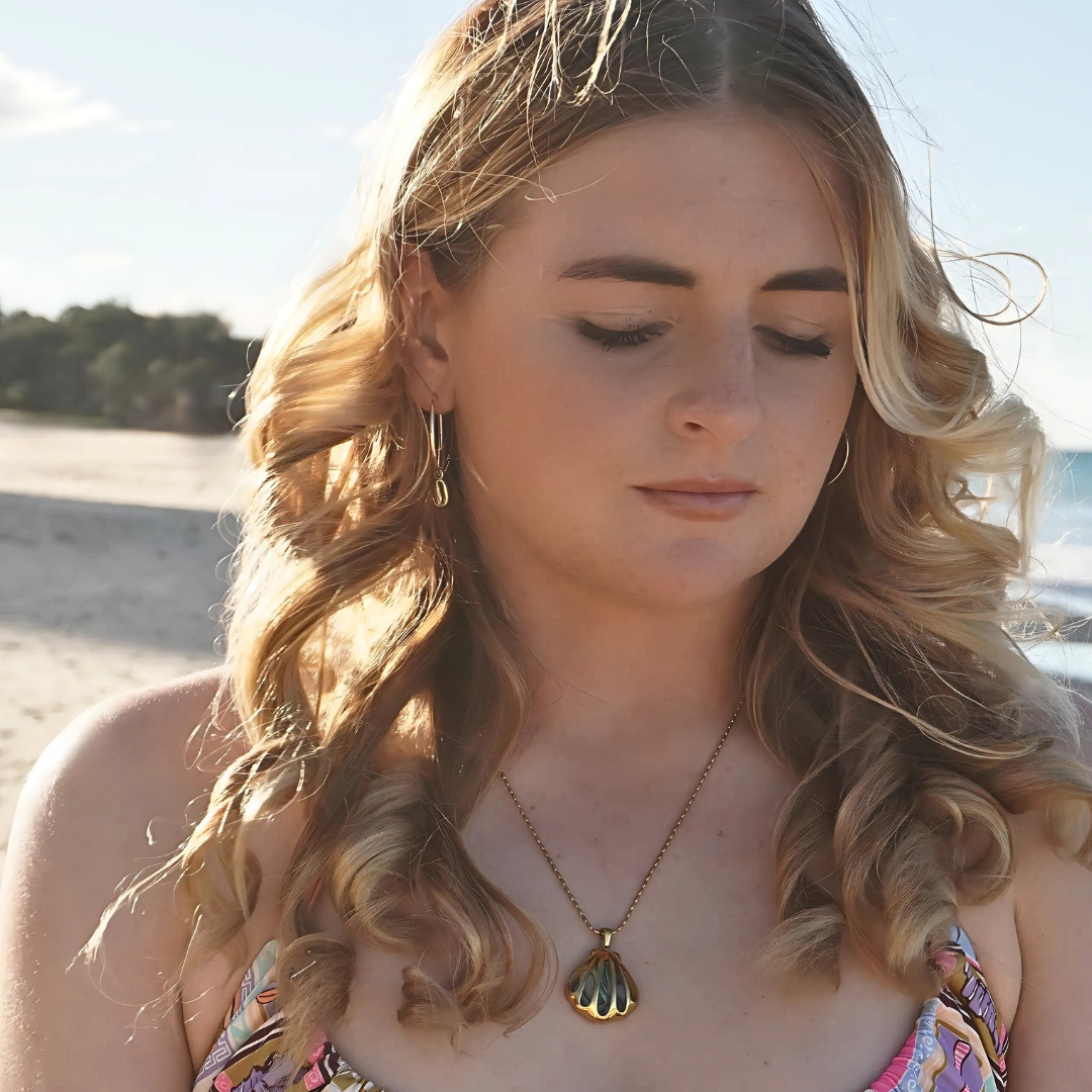 Woman wearing Large Gold Cali Hoops with cowrie pendant at the beach waterproof Kailumea