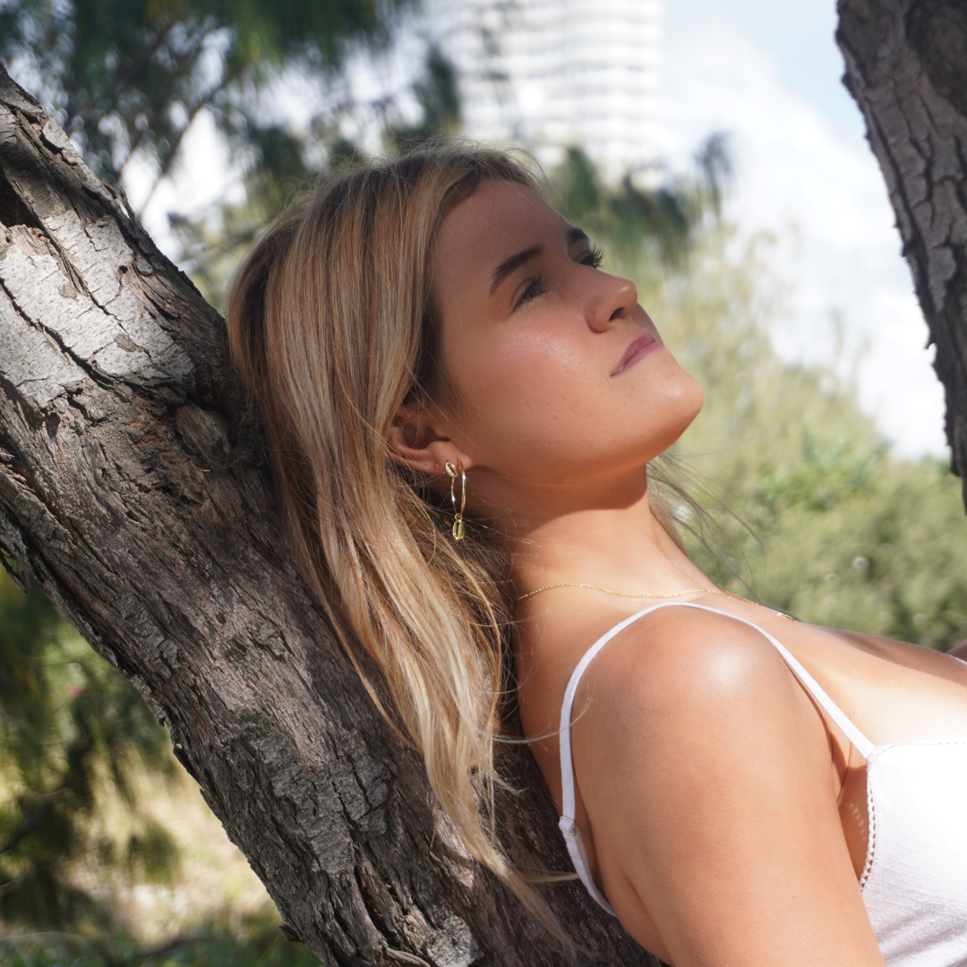 Woman wearing Large Gold Cali Hoops with cowrie pendant and Solaya necklace at the beach waterproof Kailumea