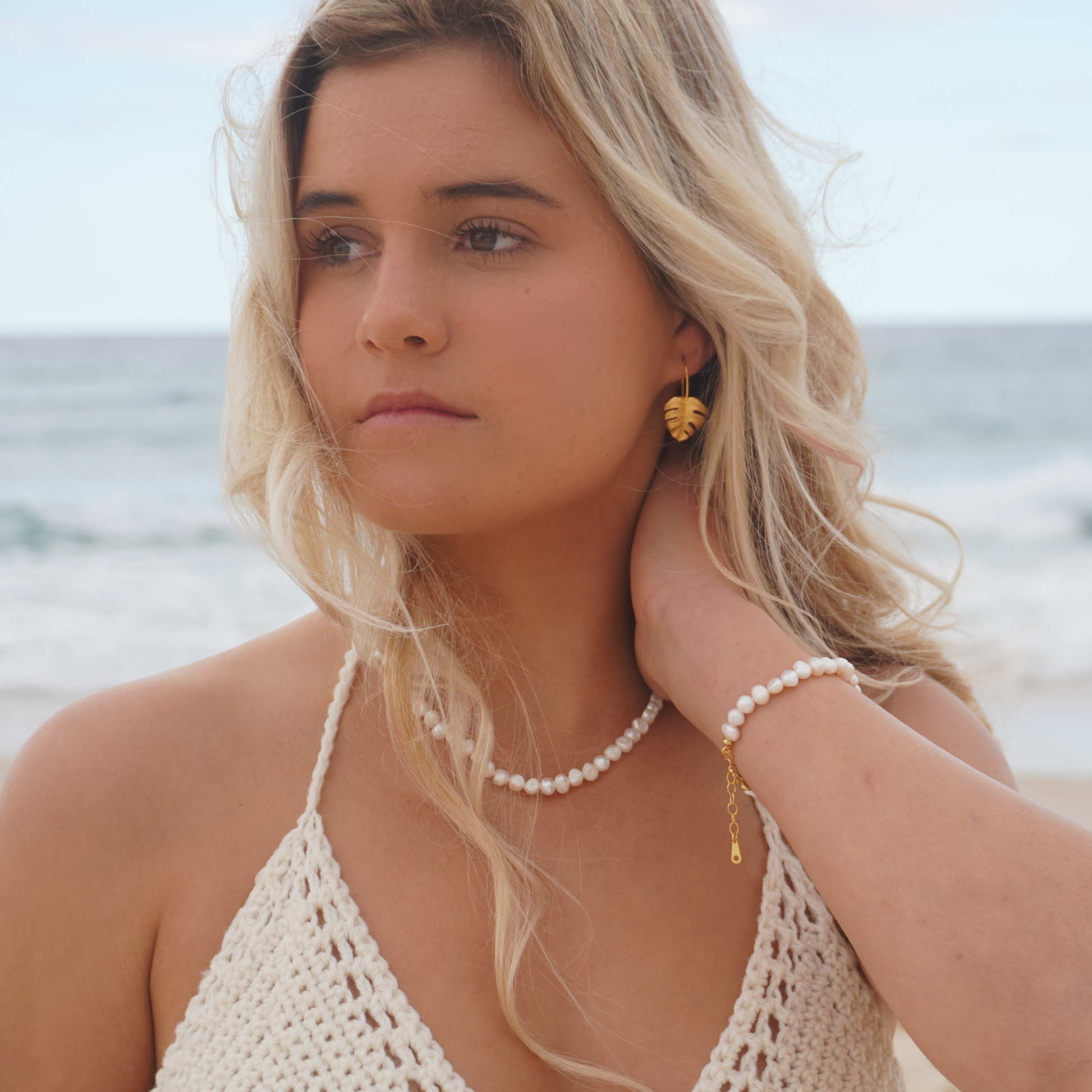 Woman wearing Gold Waterproof La Isla Threads Monstera Leaf Thread Earrings on the beach Kailumea