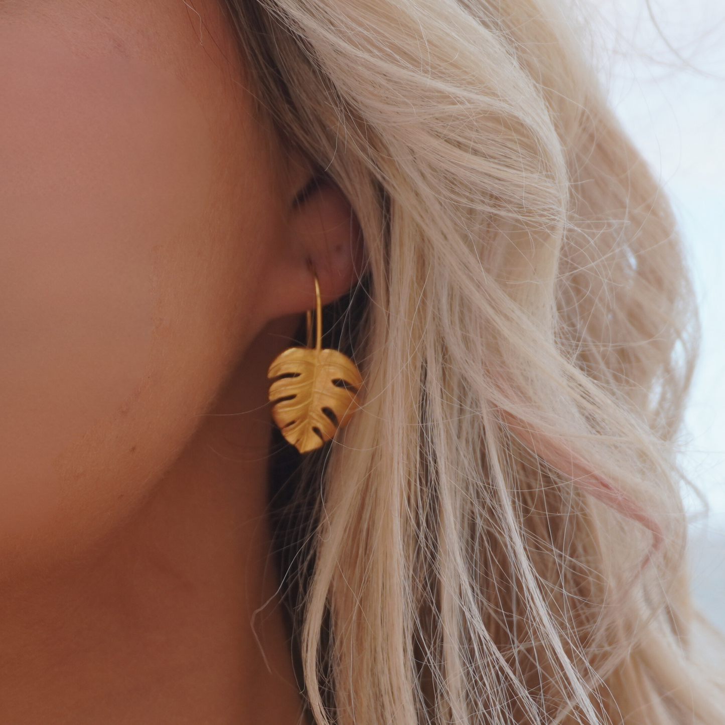 Close up in ear Woman wearing Gold Waterproof La Isla Threads Monstera Leaf Thread Earrings on the beach Kailumea