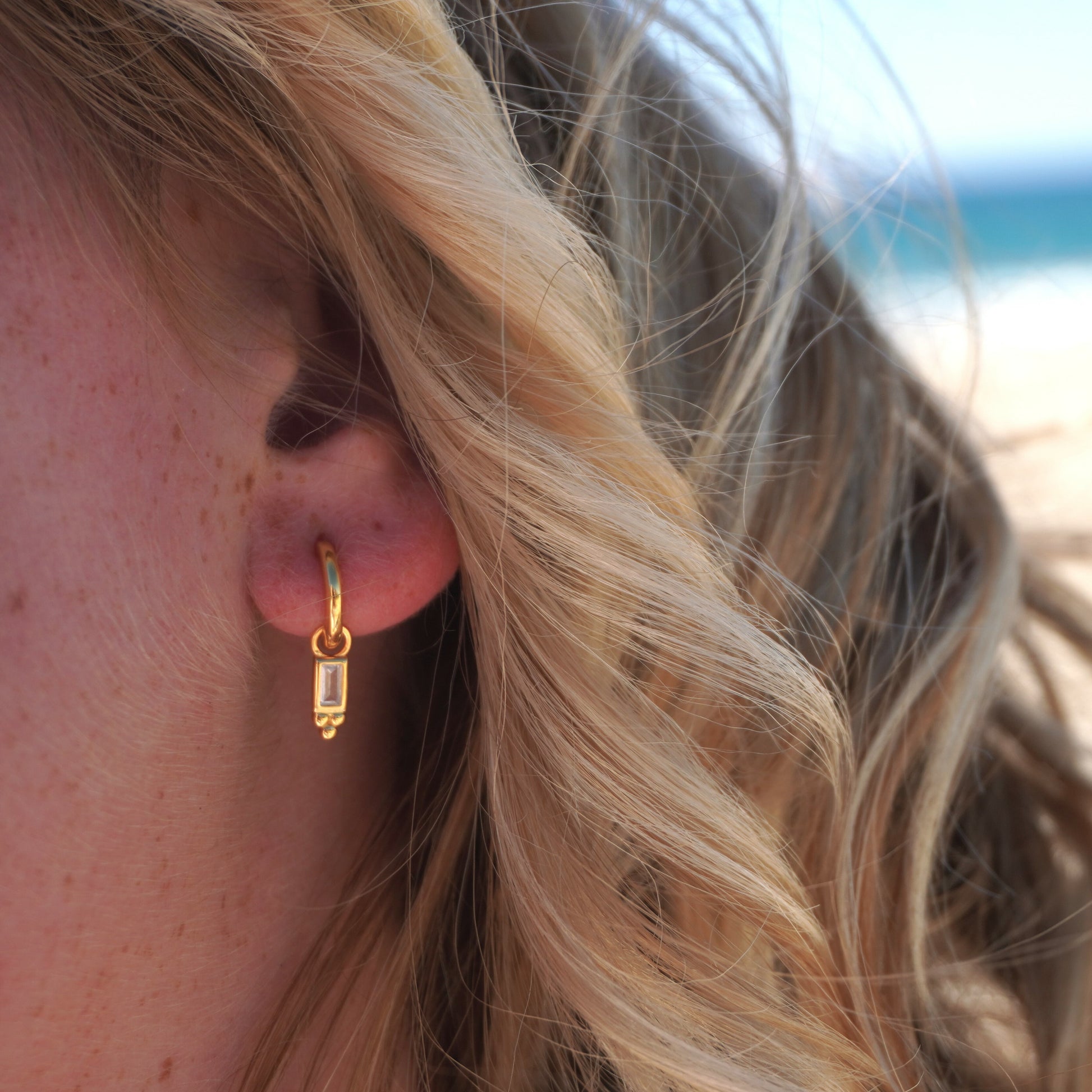 Close up in ear woman wearing Pavana Gold Baguette Stone huggie hoop earring waterproof kailumea