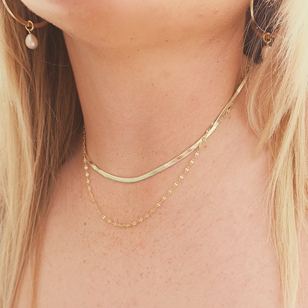 Woman wearing Zephyr Herringbone chain stacked with Mimi sparkle chain and Waikiki Hoops. waterproof gold Kailumea