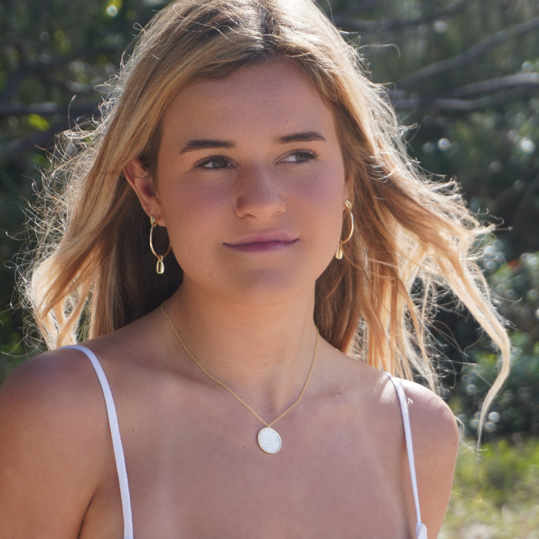 Woman wearing Large Gold Cali Hoops with cowrie pendant and Solaya necklace at the beach waterproof Kailumea