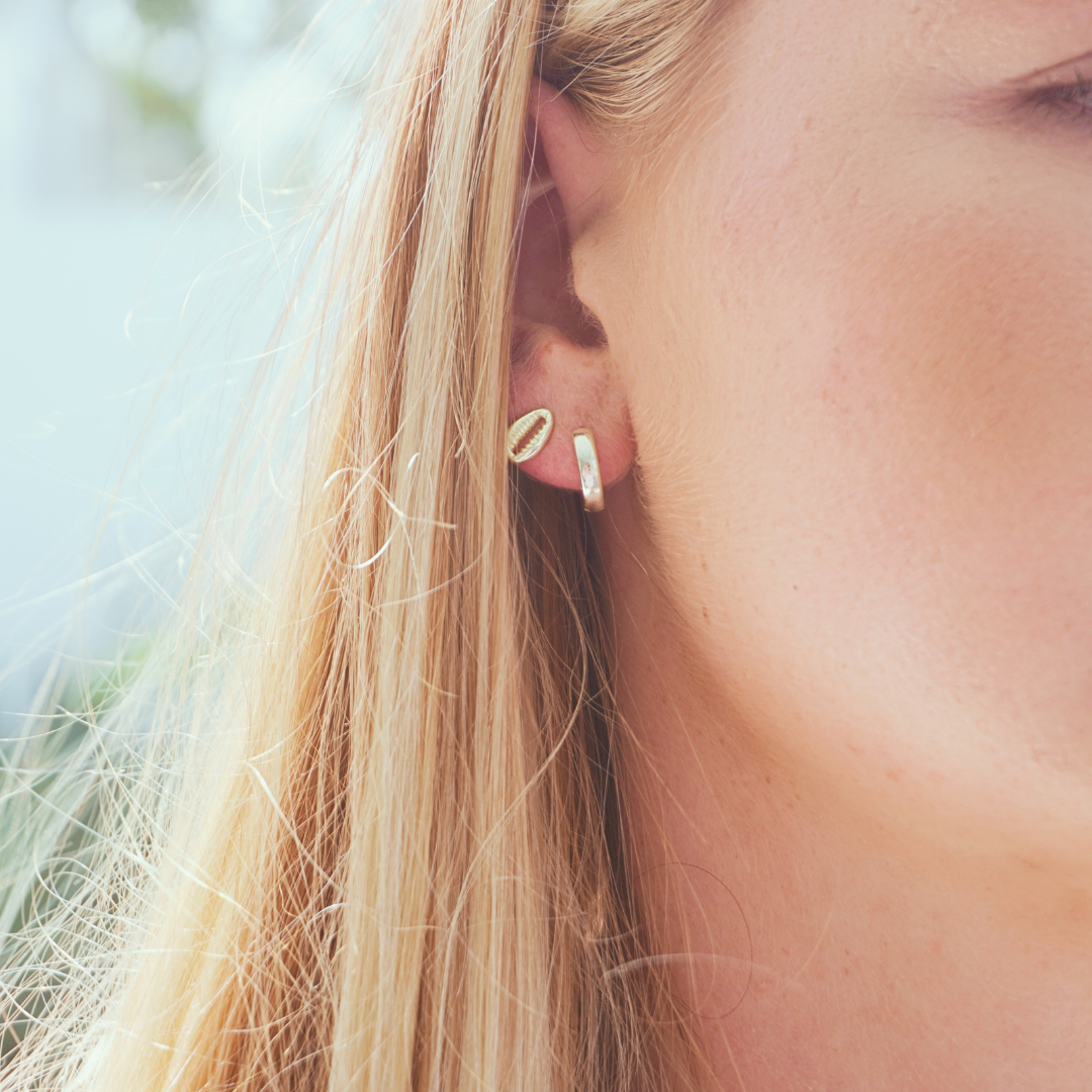 Close up in ear woman wearing Waterproof Gold Classic Small Round Hoop earrings and gold cowrie stud earrings kailumea