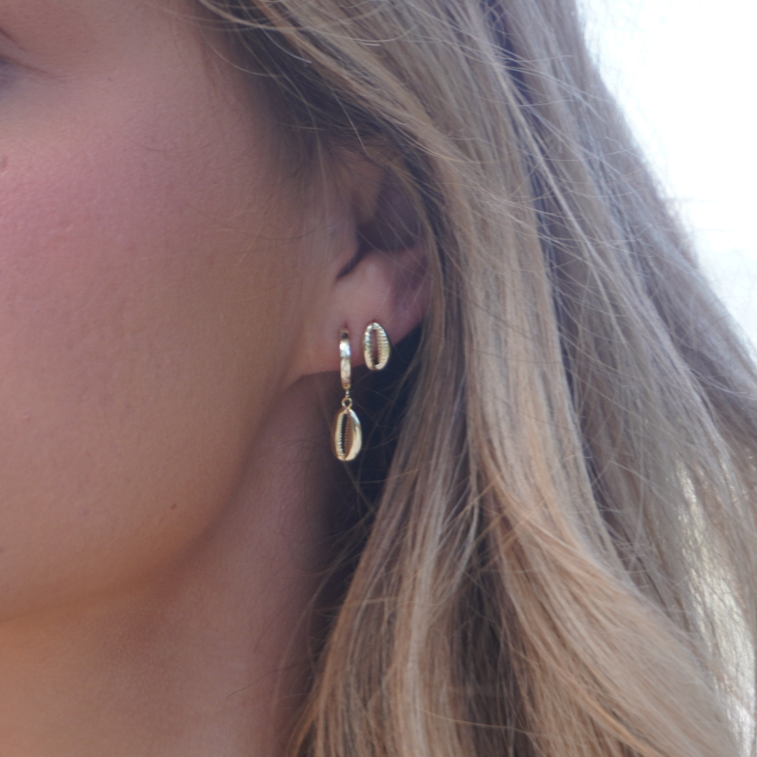 Close up in ear Woman wearing Gold Cowrie Pendant Hoop Earrings and Gold cowrie stud earrings at the beach waterproof Kailumea