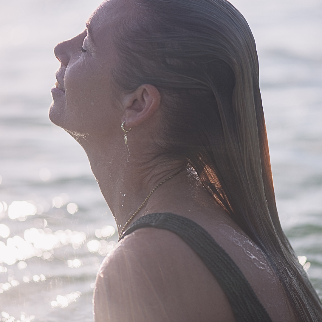 Woman wearing Iluka Gold shell hoops in the ocean. waterproof ocean-safe Kailumea