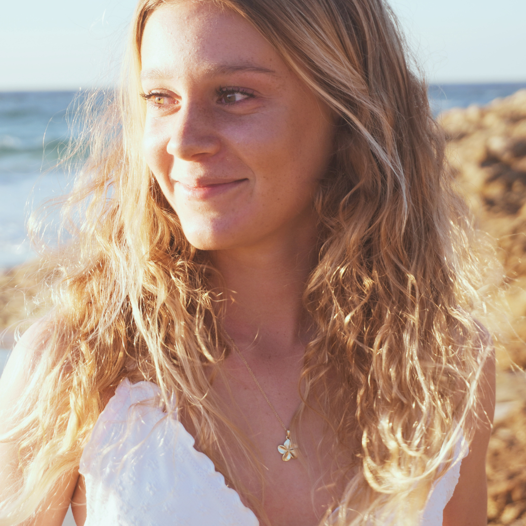 Surf girl wearing Tahiti waterproof gold frangipani necklace at beach - Kailumea