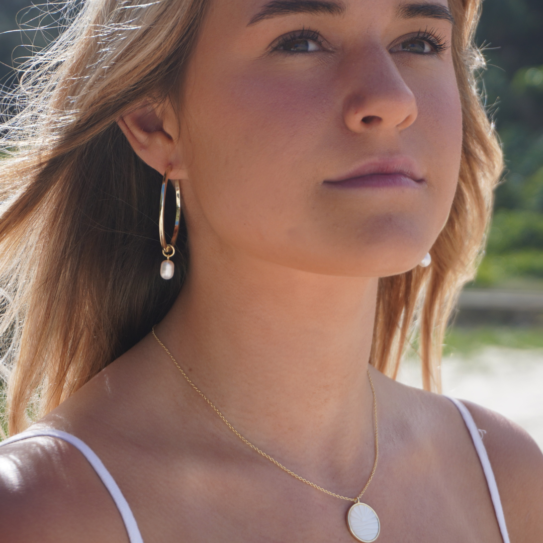 Woman wearing Waikiki Large Gold hoops with pearl charm pendant and Solaya Necklace at the beach. waterproof Kailumea