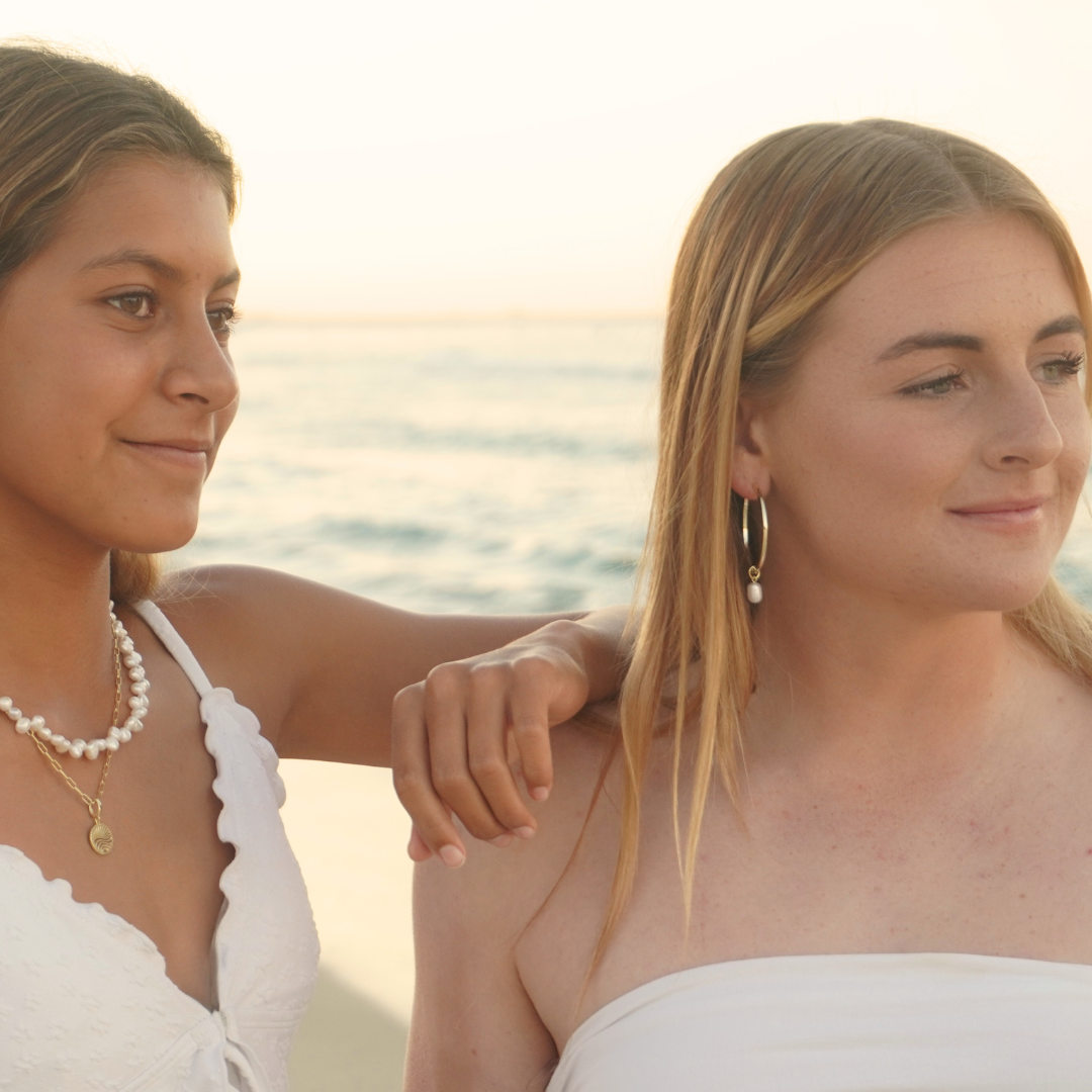 Surf girls wearing Waikiki Large Gold hoops with pearl charm pendant and Luna Tide aurora Necklace at the beach. waterproof Kailumea